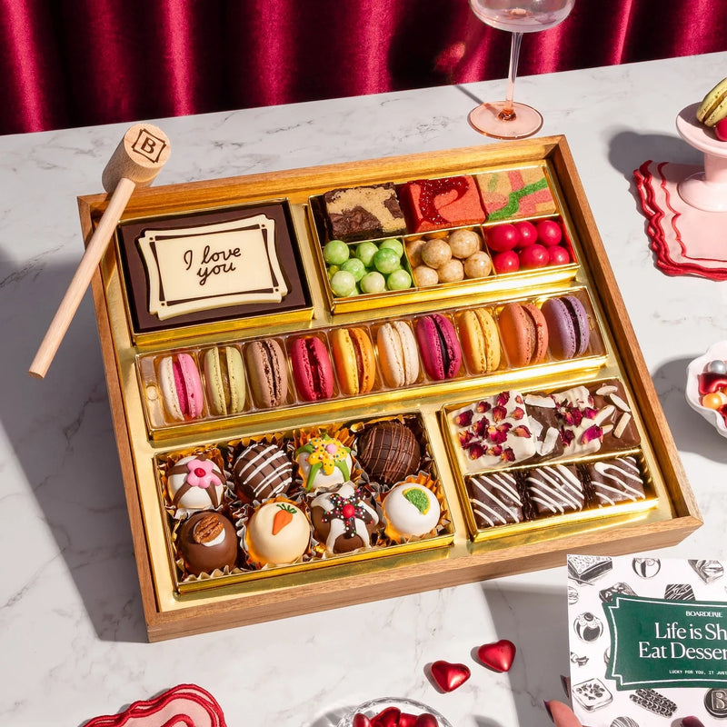 Medium Valentine's Day chocolate dessert board with "I love you" message card, macarons, bonbons, chocolate-covered berries, and decorated truffles.