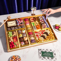 Assorted chocolates in a wooden box on a white surface with a blue curtain background.