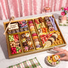 A large Easter dessert charcuterie board with macarons, chocolate-covered strawberries, truffles, carrot-shaped candies, caramel corn, and a 'Happy Easter' cookie with a chocolate mallet.