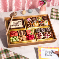 A small Easter themed charcuterie board of chocolates, truffles, candies, and a 'Happy Easter' cookie, paired with a handwritten Easter card.