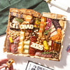 A large graduation charcuterie board topped with 'GRAD' and '2026' cheese letters, cured meats, cheeses, nuts, and dried fruits.