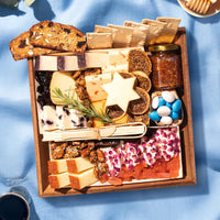 jewish holiday themed cheese board with various cheeses, crackers, and accompaniments on a blue surface.
