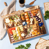 festive large charcuterie board loaded with various cheeses, dried fruits, nuts, crackers, & decorative jam jars