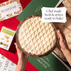 Ready-to-bake holiday brie with lattice crust, shown in packaging with Boarderie branding on a festive table.