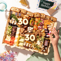 Birthday cheese board featuring an assortment of cheeses, nuts, dried fruits, and 