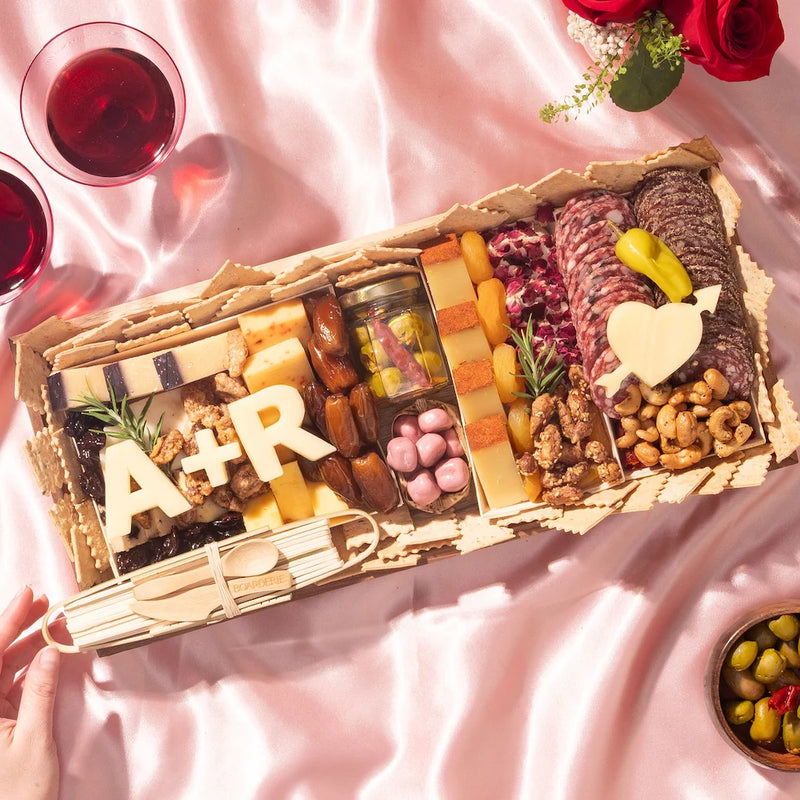 Engagement & anniversary charcuterie board with meats, cheeses, nuts, and personalized cheese cutouts of initials and a heart.