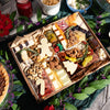 A Christmas charcuterie board with gingerbread-man and Christmas-tree shaped cheeses, cured meats, nuts, olives, and dried fruits, styled with holiday greenery.