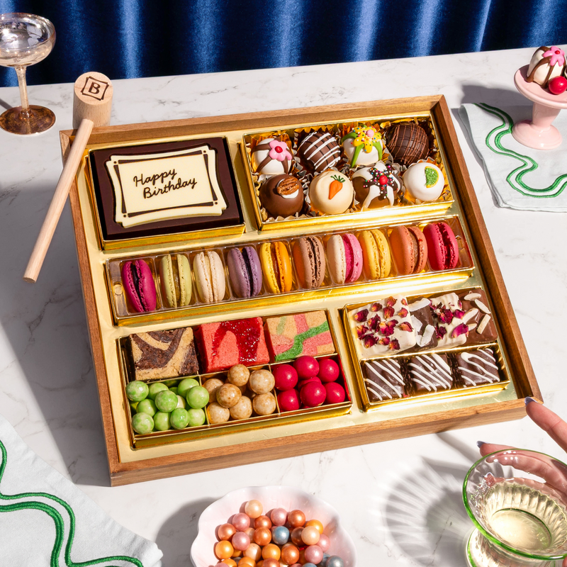 Medium dessert gift box with "Happy Birthday" chocolate card, macarons, bonbons, chocolate-covered berries, cake slices, and candies on marble surface