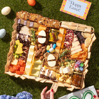Charcuterie Easter board with cheeses, nuts, dried fruits, jam, candy eggs, and festive bunny and egg-shaped cheese cutouts.
