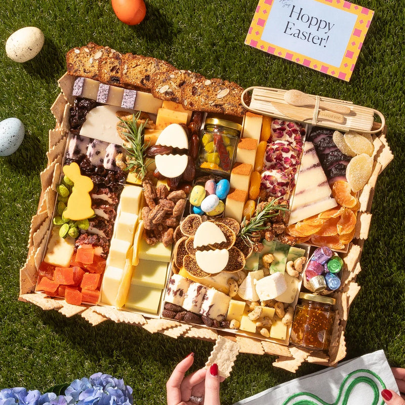 Charcuterie Easter board with cheeses, nuts, dried fruits, jam, candy eggs, and festive bunny and egg-shaped cheese cutouts.