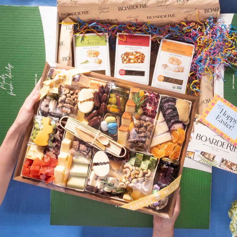 Easter charcuterie box filled with cheeses, nuts, fruits, jams, and festive cheese cutouts shaped like eggs and a bunny.