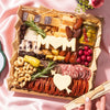 Mother’s Day brunch charcuterie board with cheeses, meats, nuts, fruit, and cheese cutouts shaped like “MOM” and a heart.