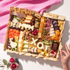Mother's Day cheese board with assorted cheeses, dried fruits, nuts, and "MOM" and "XO" cutouts in cheese.