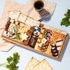 Passover charcuterie board with matzo, artisanal cheeses, dried fruits, nuts, fig jam, and star-shaped cheese cutouts.
