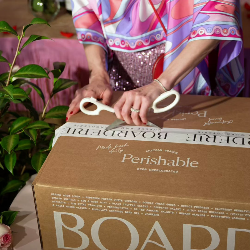 Valentine’s Day charcuterie board being unboxed from a large labeled cardboard box with decorative packaging.