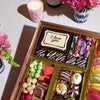 Gourmet dessert gift board featuring over 47 artisan chocolates, brownies, macarons, cakes, truffles, caramels & more on a reusable acacia wood board. Smash the chocolate box for a surprise.