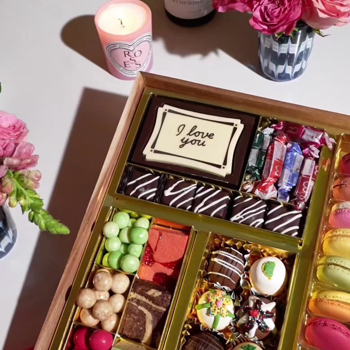 Gourmet dessert gift board featuring over 47 artisan chocolates, brownies, macarons, cakes, truffles, caramels & more on a reusable acacia wood board. Smash the chocolate box for a surprise.