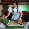 video of girl unboxing a frozen baked brie with mummy decoration on the pastry. Baked brie is baked in the over and cut open on a halloween themed table.