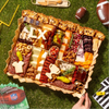 Super Bowl charcuterie board with gourmet cheeses, meats, nuts, and cheese cutouts shaped like a helmet, jersey, and “LX.”