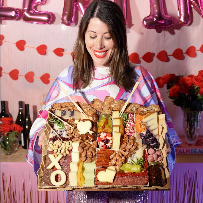 Cheese board for Valentine’s Day featuring gourmet cheeses, meats, nuts, and heart-shaped cheese cutouts with XO lettering.
